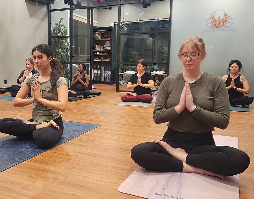 Students in a seated practice at The Mind-Body Connection, hands at heart
